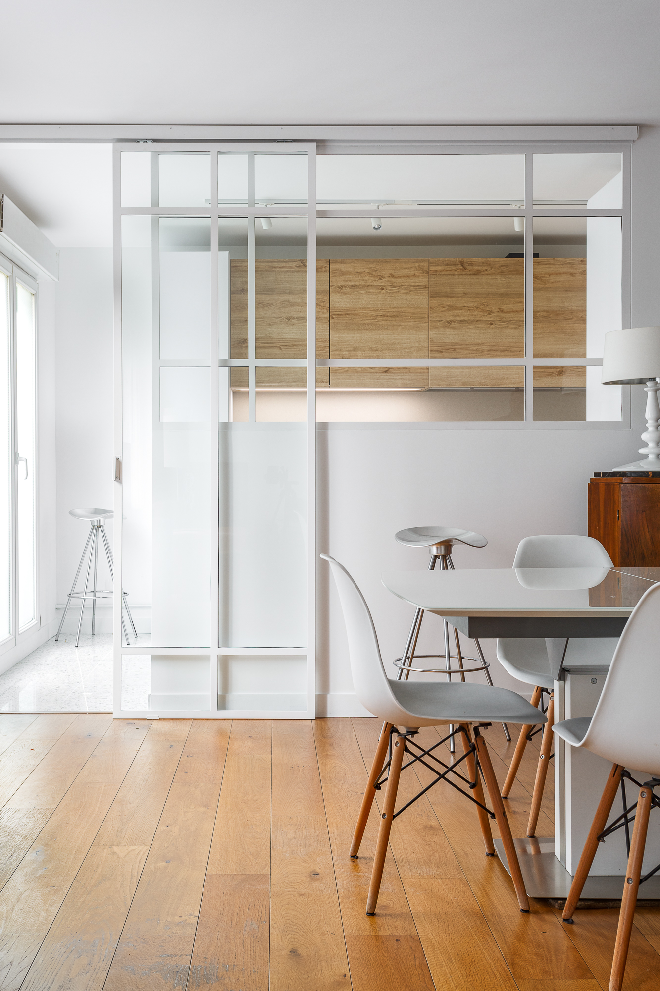Séjour avec verrière blanche et table en verre, appartement Paris 17