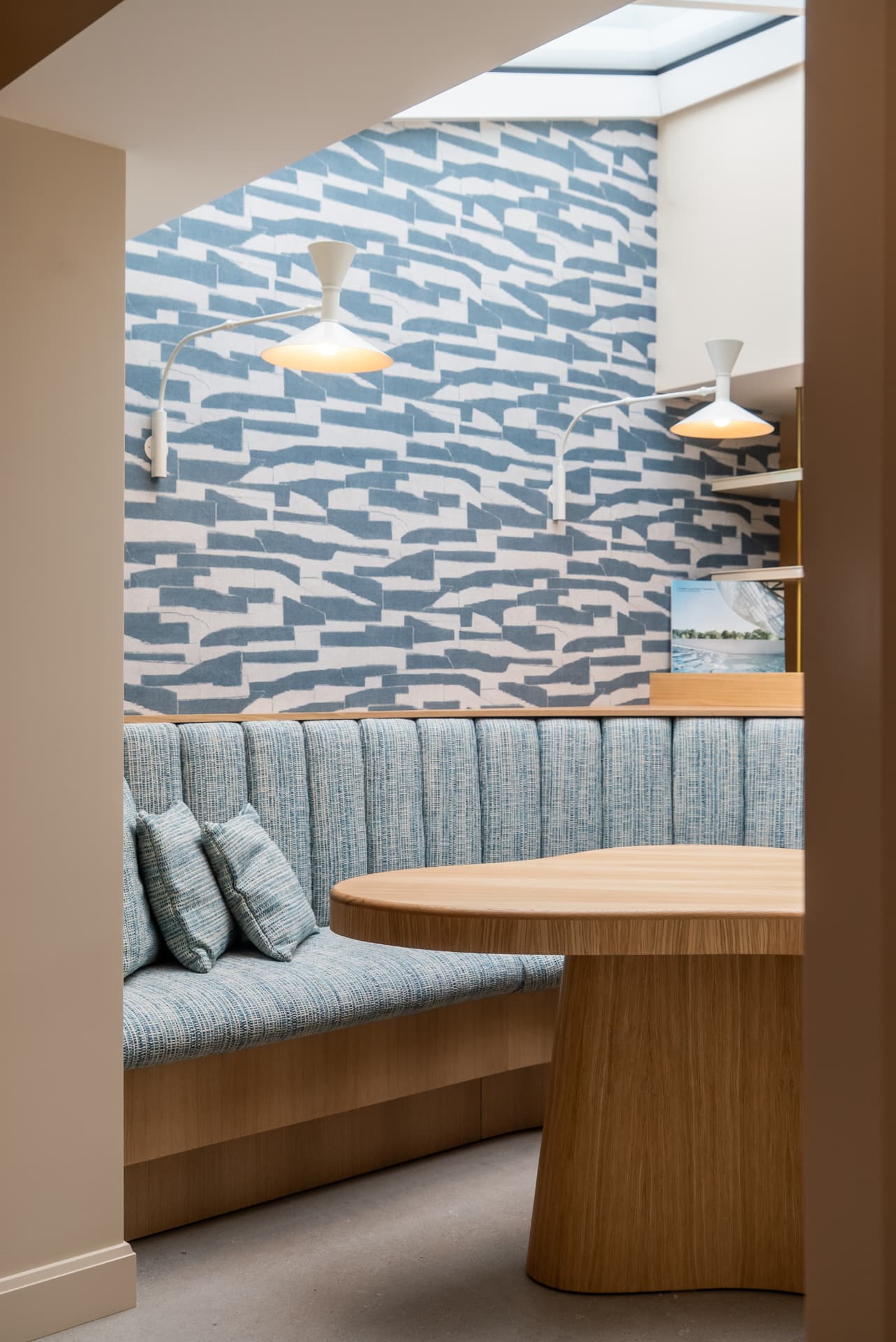 Coin repas avec banquette sur mesure et papier peint graphique bleu, maison de bord de mer en Normandie