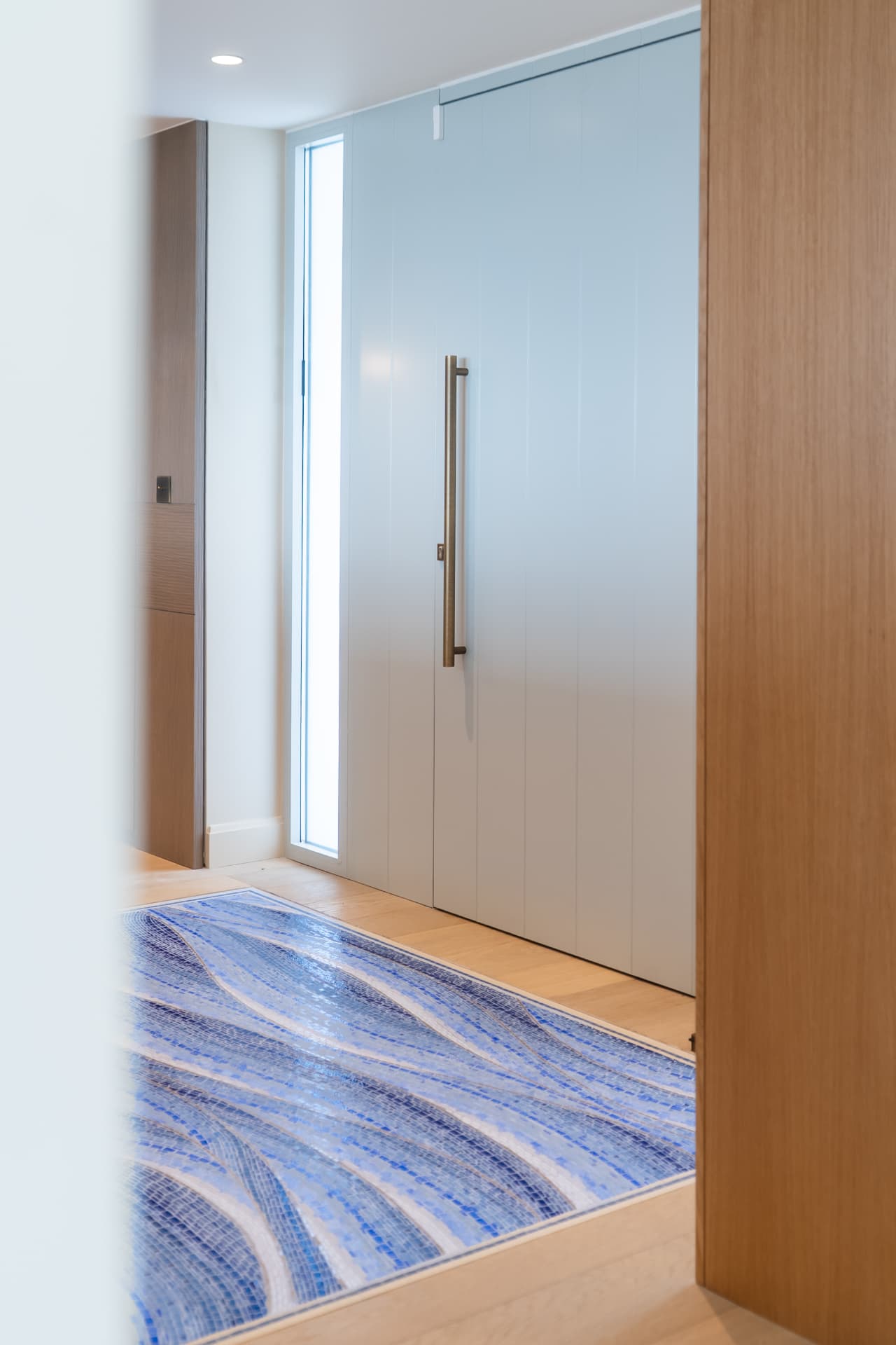 Entrée avec tapis en mosaïque bleue et menuiseries sur mesure, maison de bord de mer en Normandie