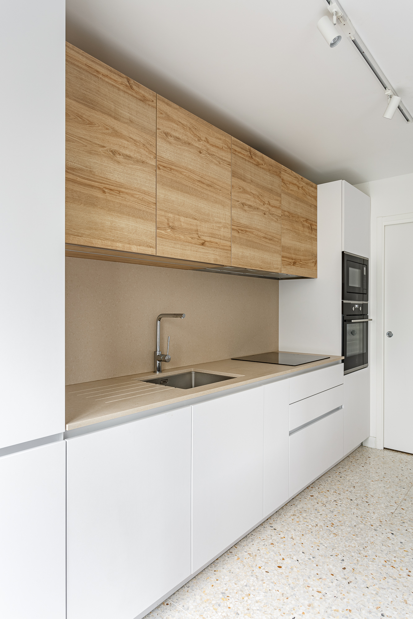 Cuisine blanche avec façades chêne et plan de travail beige, appartement Paris 17