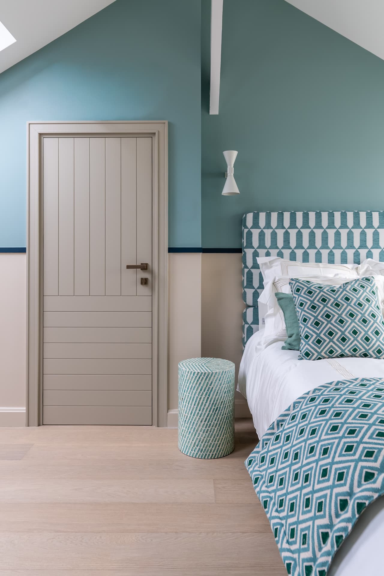 Chambre aux murs bleu-vert et textiles géométriques, maison de bord de mer en Normandie