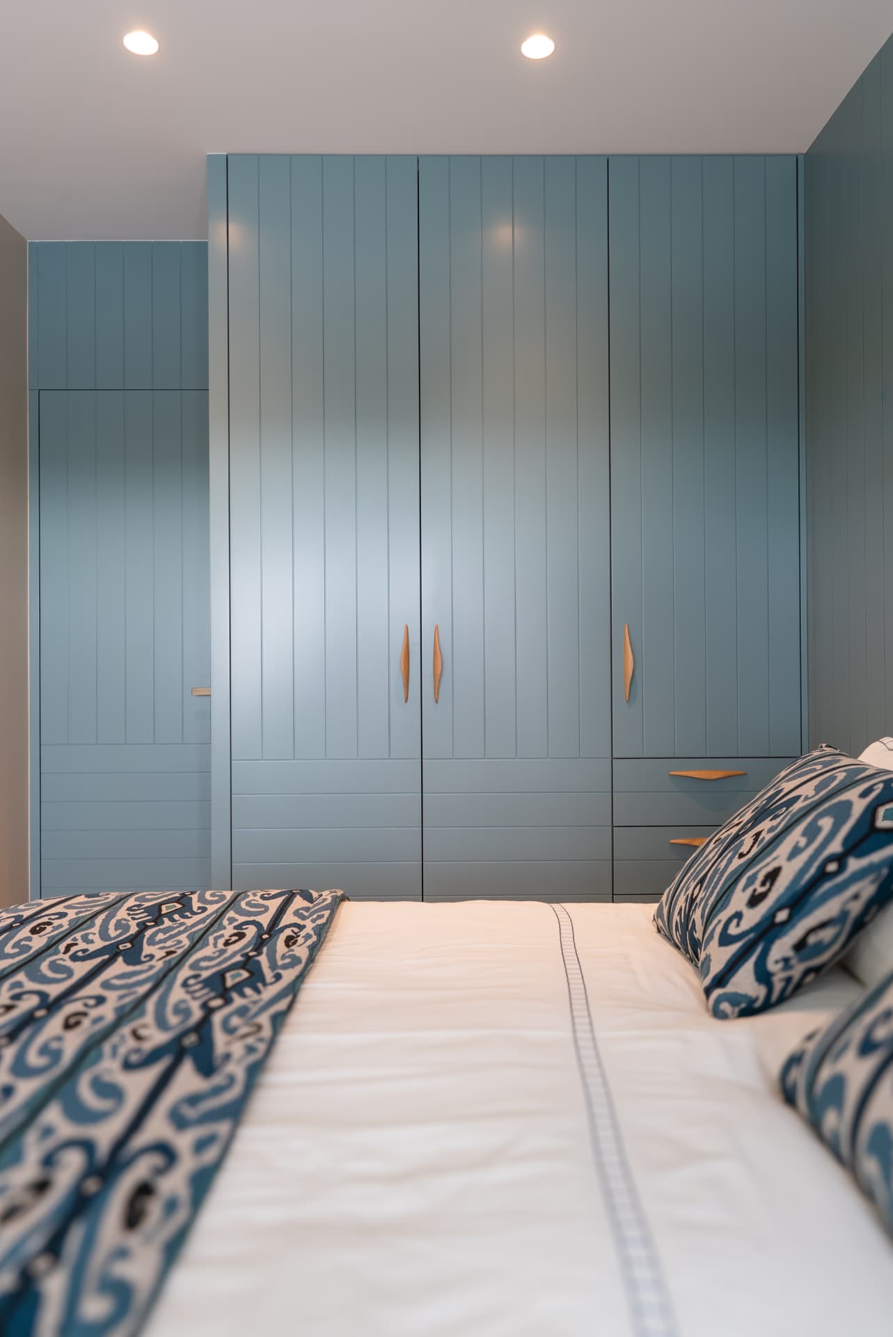 Chambre avec dressing bleu clair et textiles à motifs, maison de bord de mer en Normandie