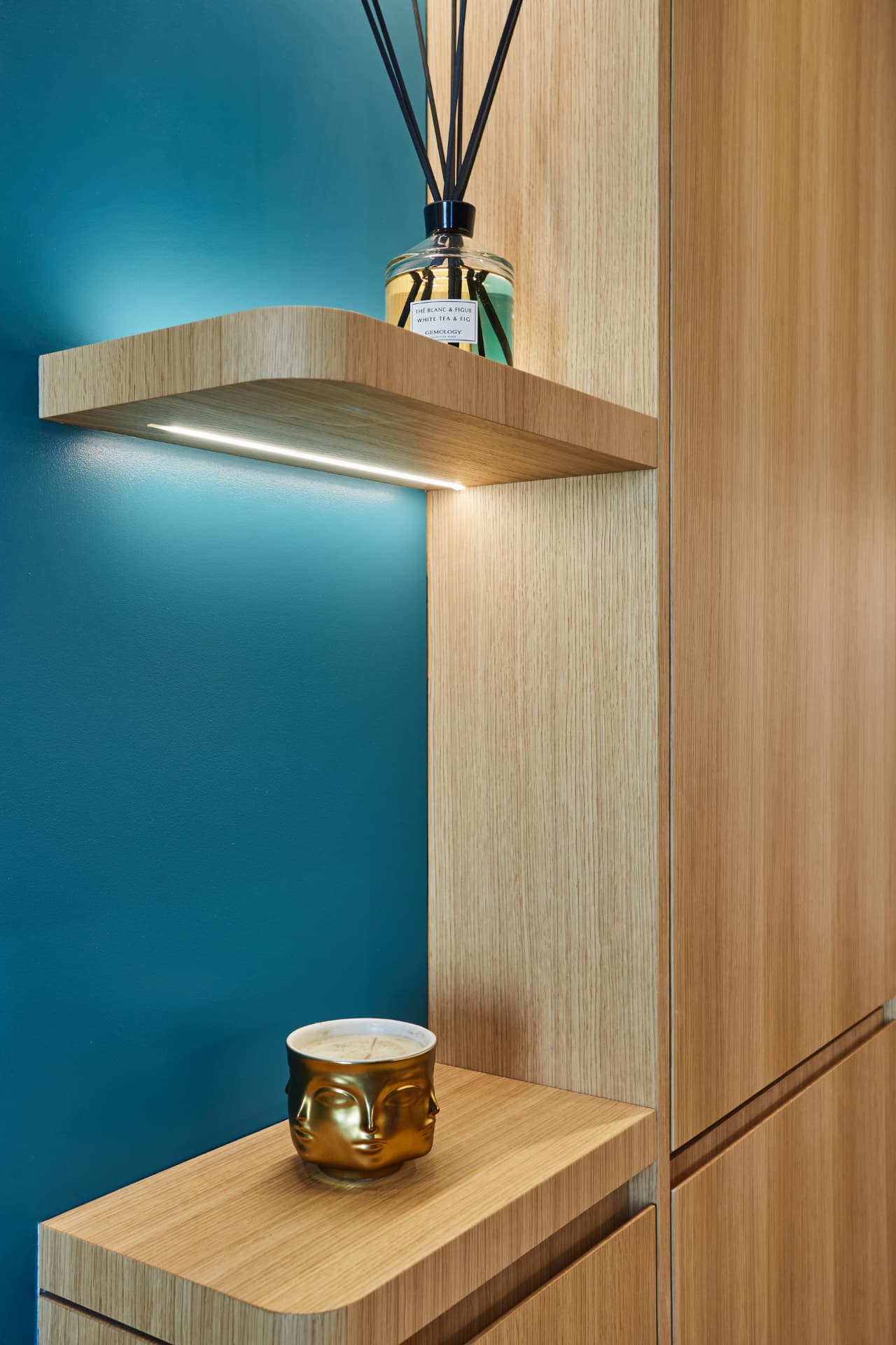 Étagère en chêne éclairée et mur bleu, détail cuisine appartement Paris 16